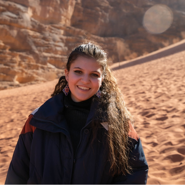 Ariana Siddiqui Dennis in front of a cliff in Jordan