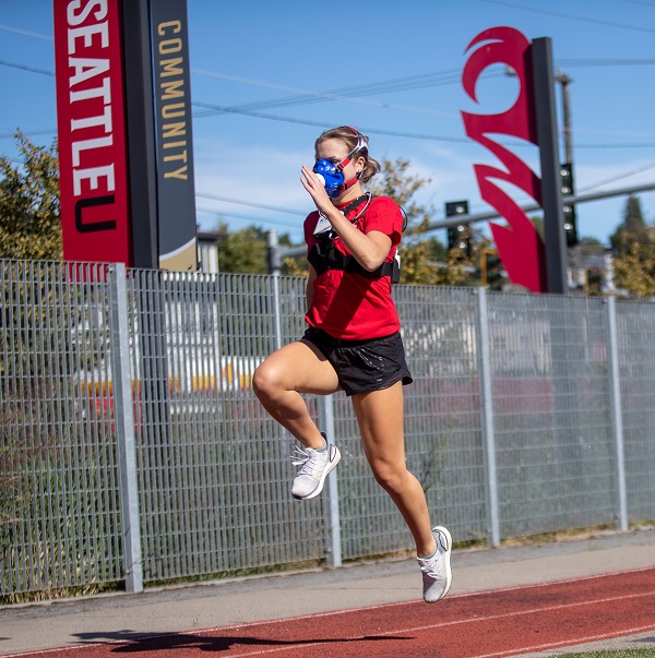 Woman in red shirt and black shorts, running, wearing device