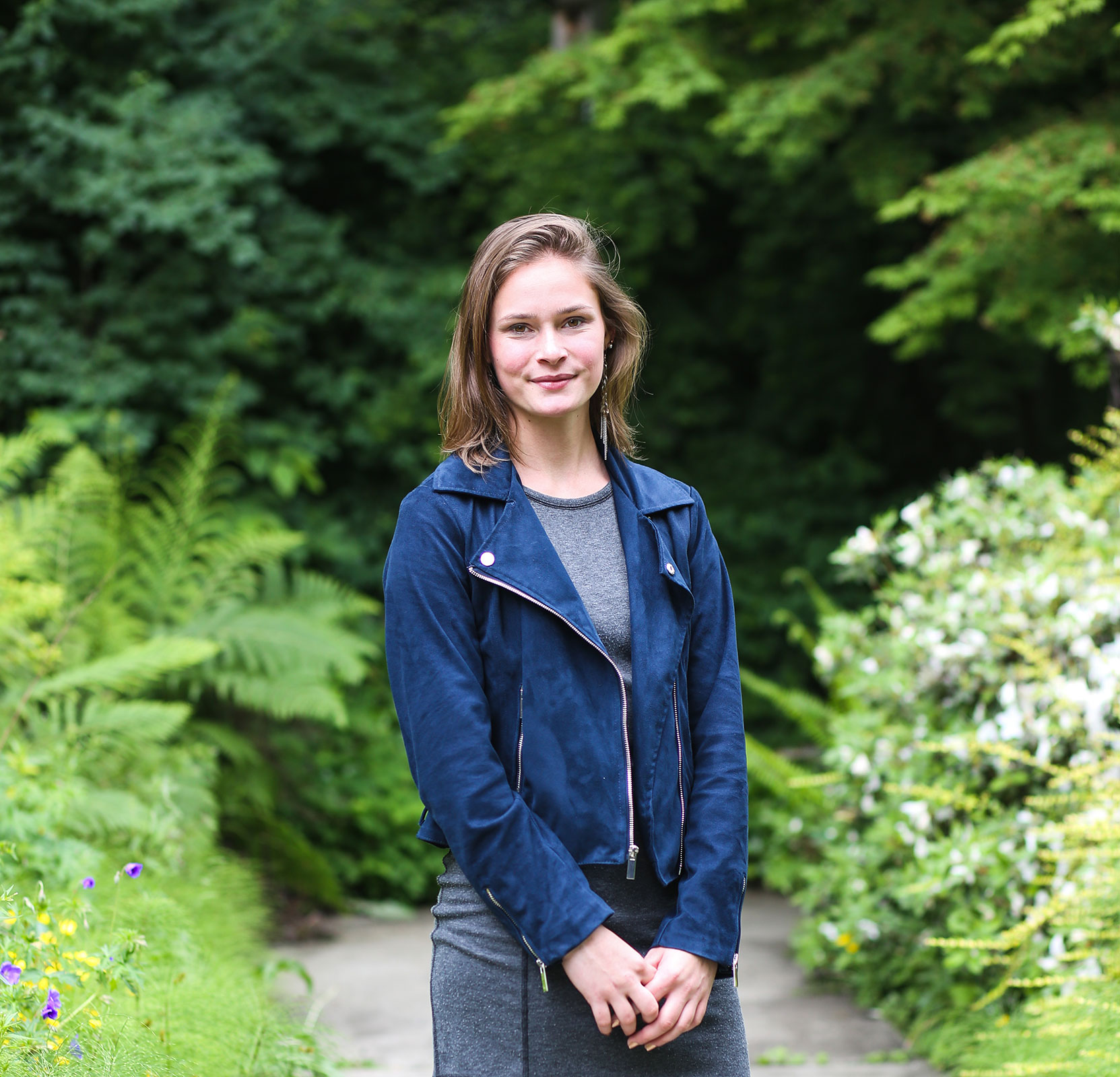 Emily standing outside in front of greenery.