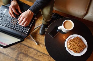 Top view of laptop, coffee and coffee bread