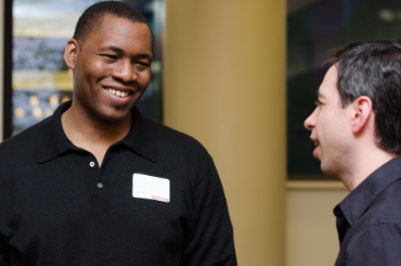 An African American male talking to a while make in a professional setting