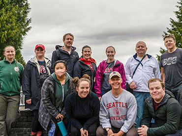 Group of alumni posing against a gray sky