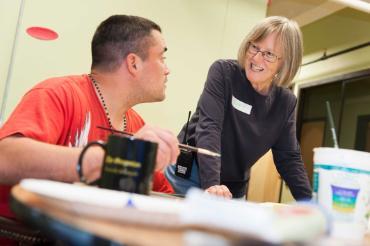 A JV Encorps Volunteer talking to a male in an artroom