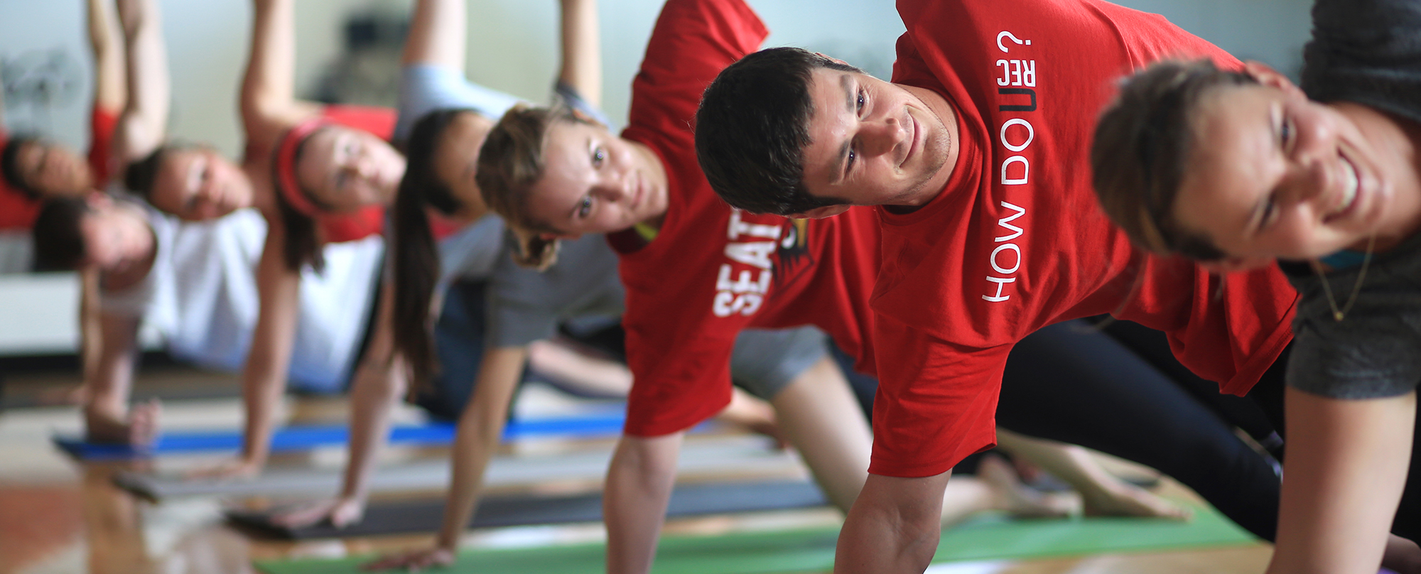 A group of people do a yoga pose during a class at Seattle U's Eisiminger Fitness Center