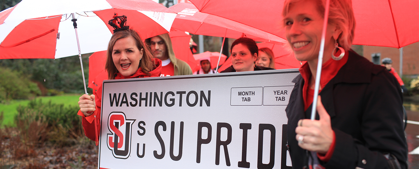 A group of alums hold an oversized Seattle U license plate