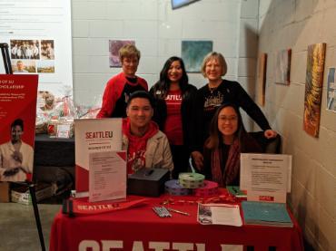 A group of five women sitting behind a check-in table at a Women of SU Fundraising event