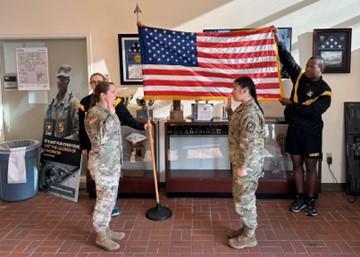 Cadet and LTC Maier in front of flag hands raised in oath