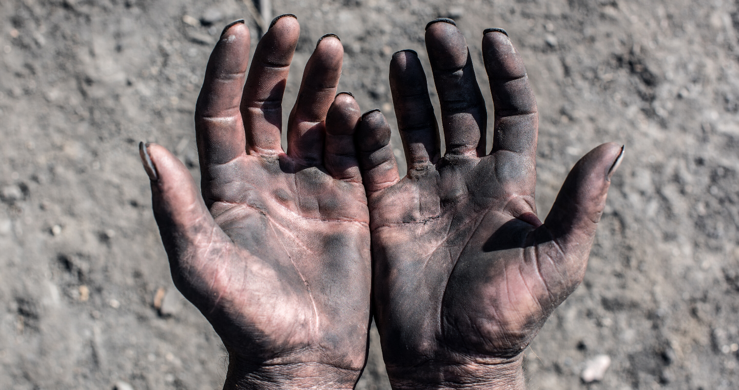 an image of hands outstretched, palms up, covered in dirt