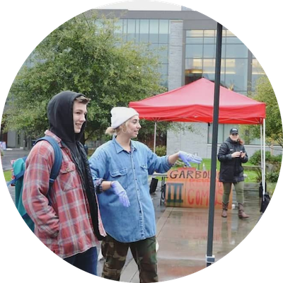 one SU student directs another towards the garbology event in the library lawn