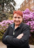 Photo of Dr. Kirsten Thompson in front of flowering shrubs