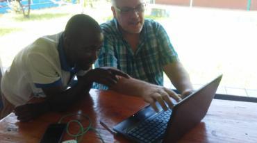 Eric Muhs and a student in Guinea, looking at a computer