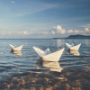 Three paper sailboats near the ocean shore