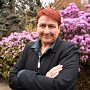 Photo of Dr. Kirsten Thompson in front of flowering shrubs