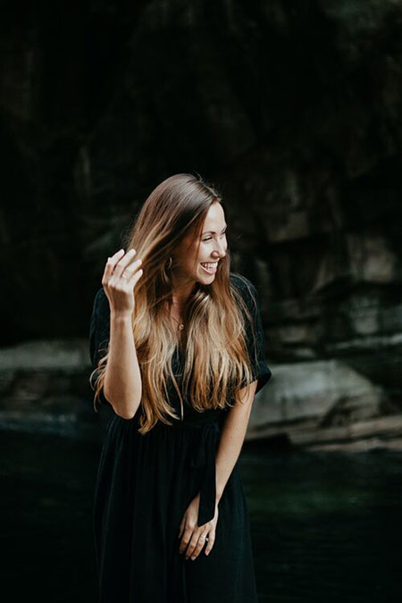 photograph of curator Arielle Simmons against a black background with a hand pulling back long hair.