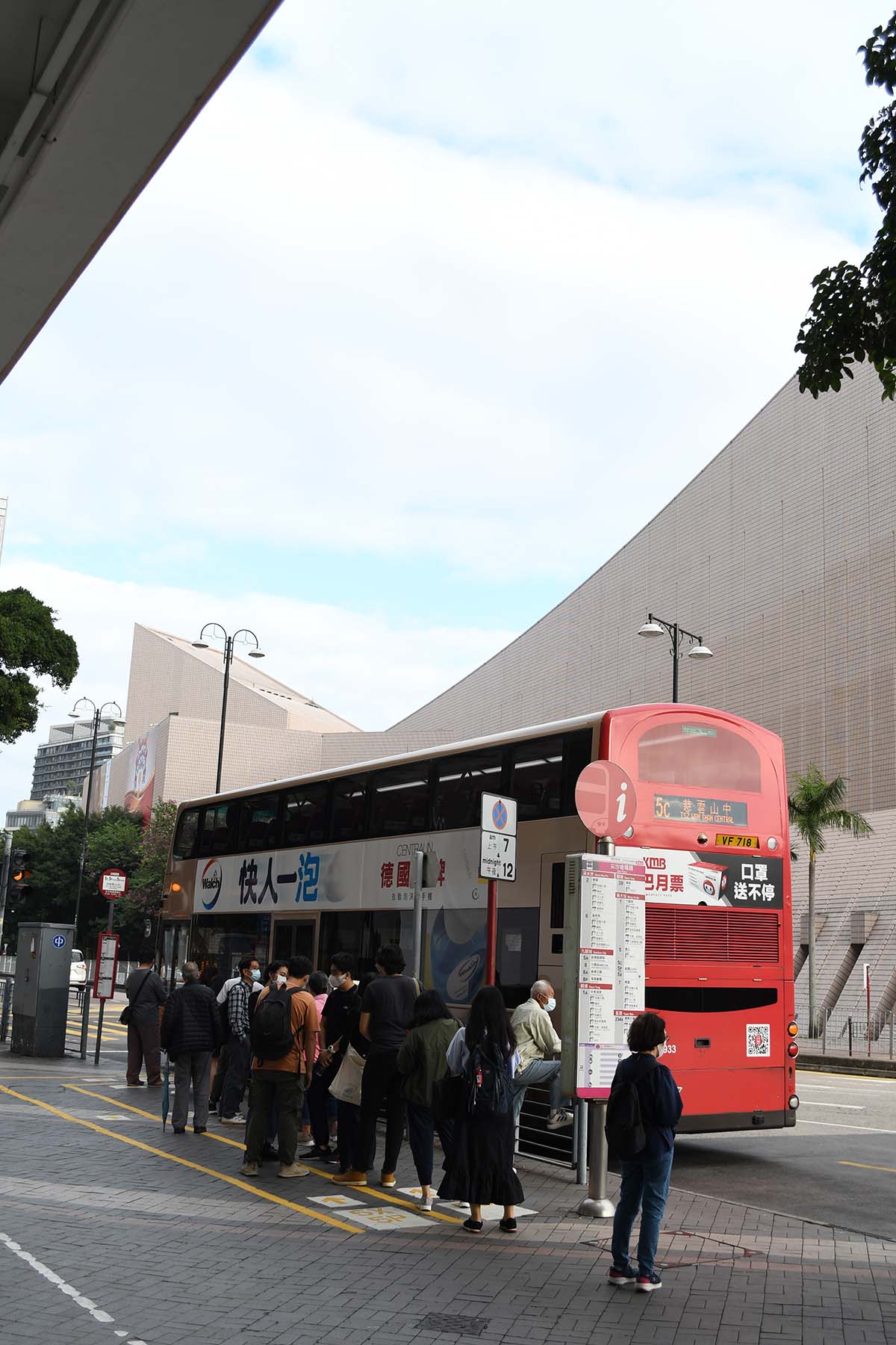 photograph of the side of a bus with a line of people waiting 