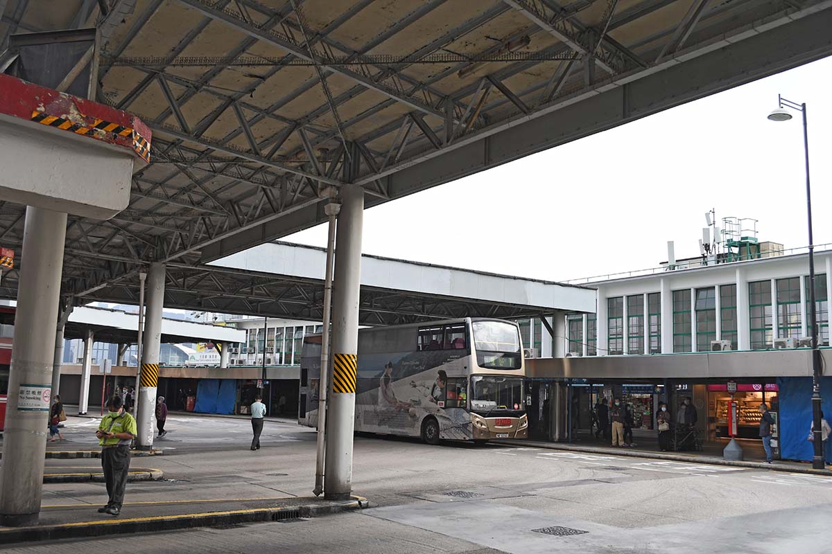 photograph of a person under a covered area with a bus in the background