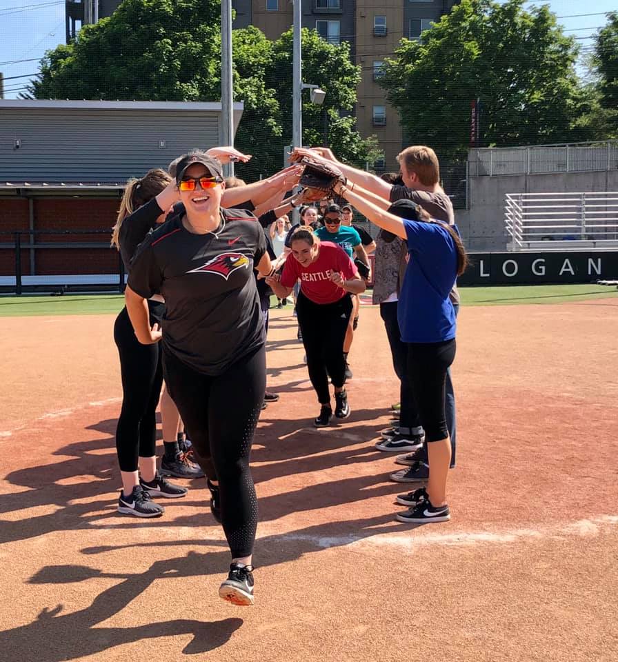 People on a softball field making a tunnel while other people run under