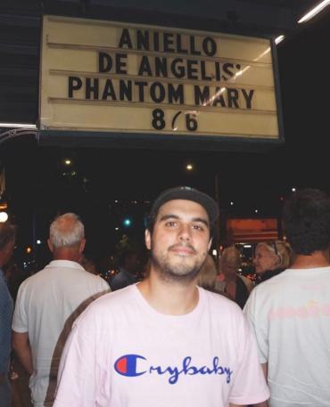 A man standing in front of a crowd and a sign titled 