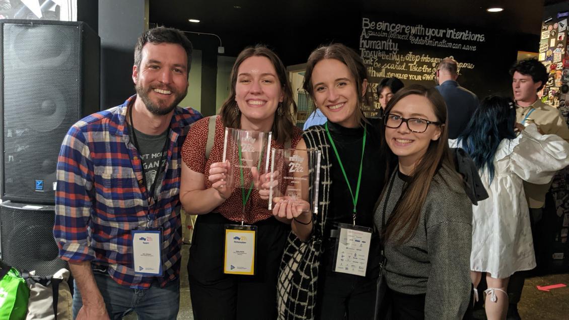 Alumni filmmakers smiling for a photo with their awards.