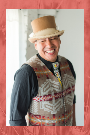 Kasey Nicholsen in top hat and vest with orange background