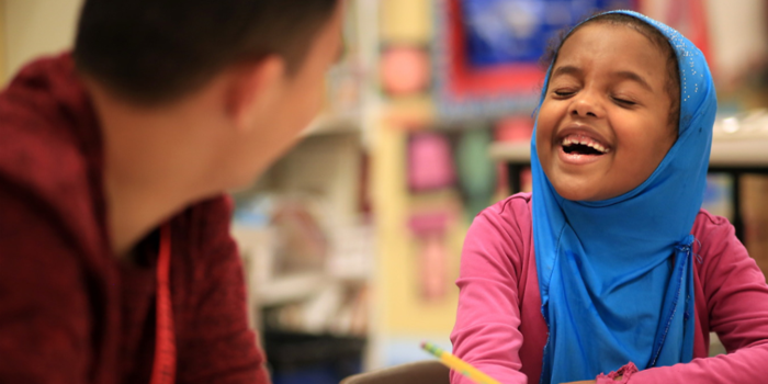 Education and teaching - School child laughing with teacher in a classroom