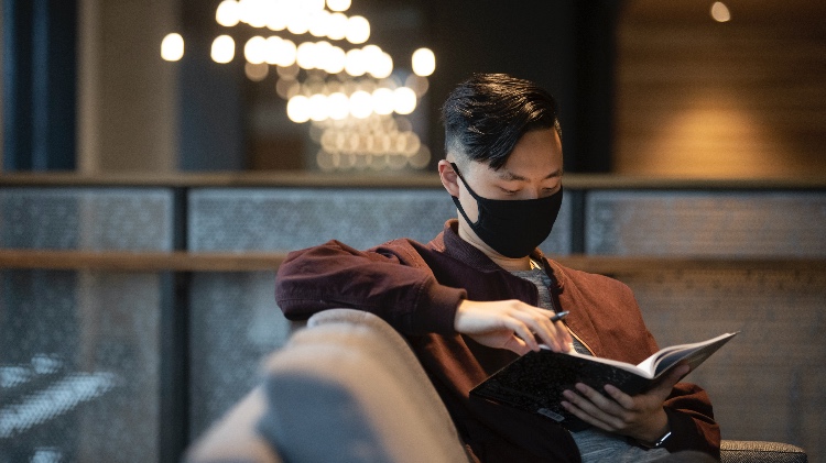 Student reading a book and wearing a mask