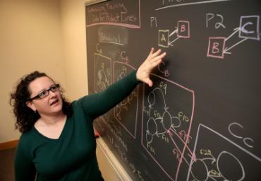 Faculty member pointing to a chalkboard