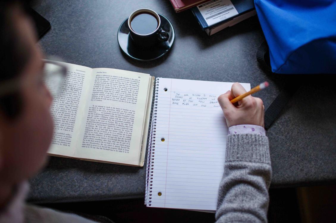 Writing notes in notebook while reading.