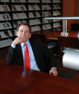 David Powers in dark suit and red tie in library