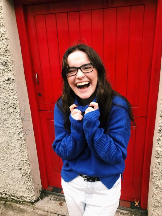 A student in front of a wall smiling