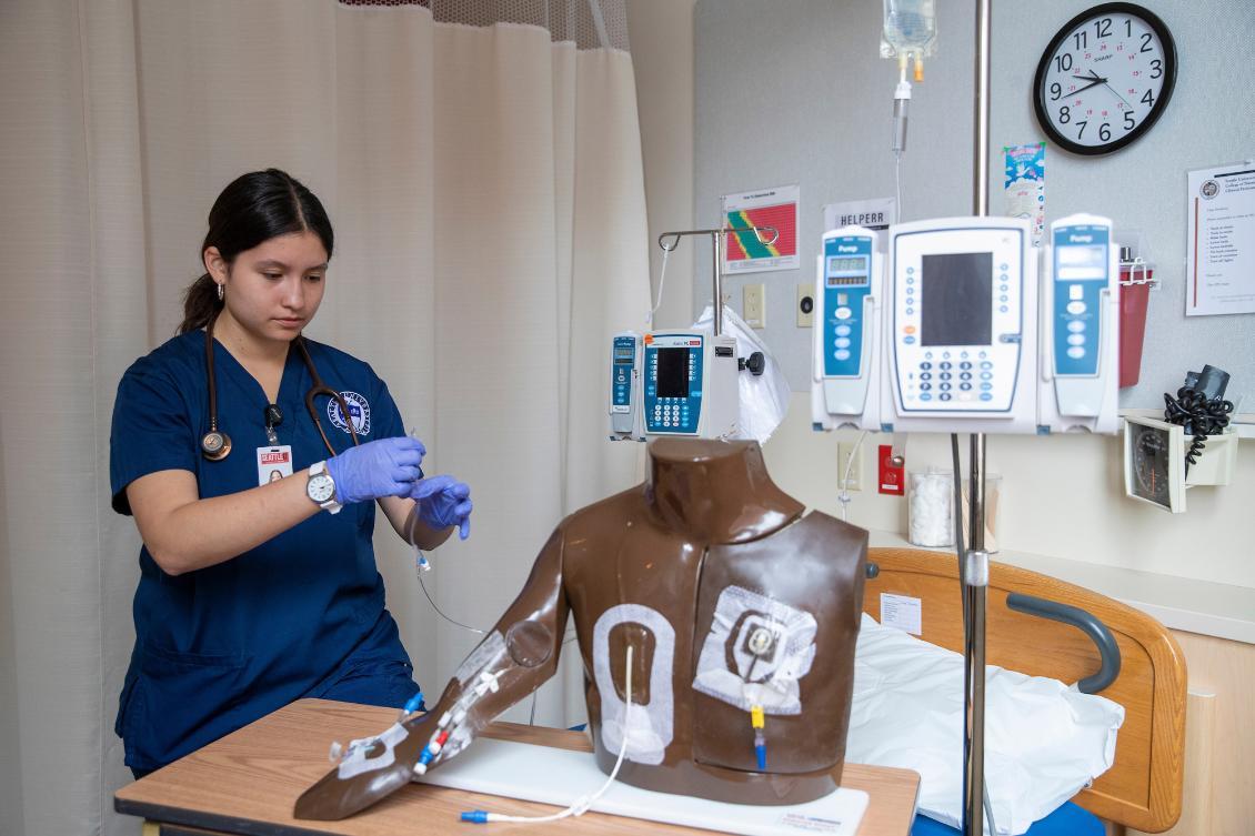 Nursing sudent in lab practiing skills with low-fidelity manikin