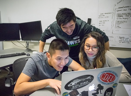 Students look at a computer together, collaborating on their Industry sponsored capstone project.