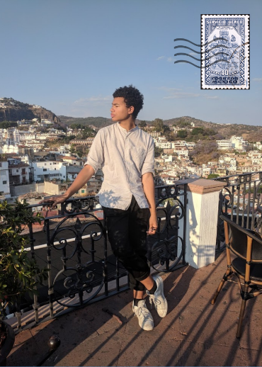 Man looking out at a town while leaning on a fence