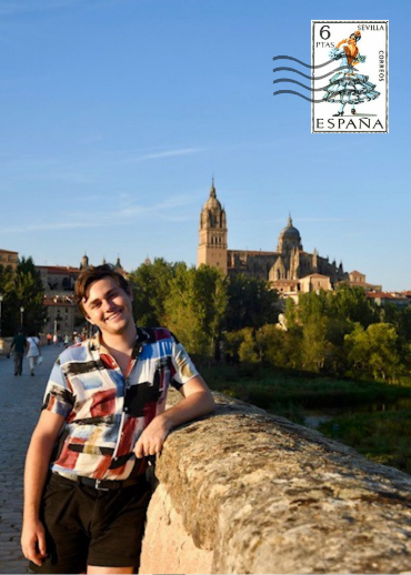 man with his head tilted smiling at the camera on a bridge with a castle in the background