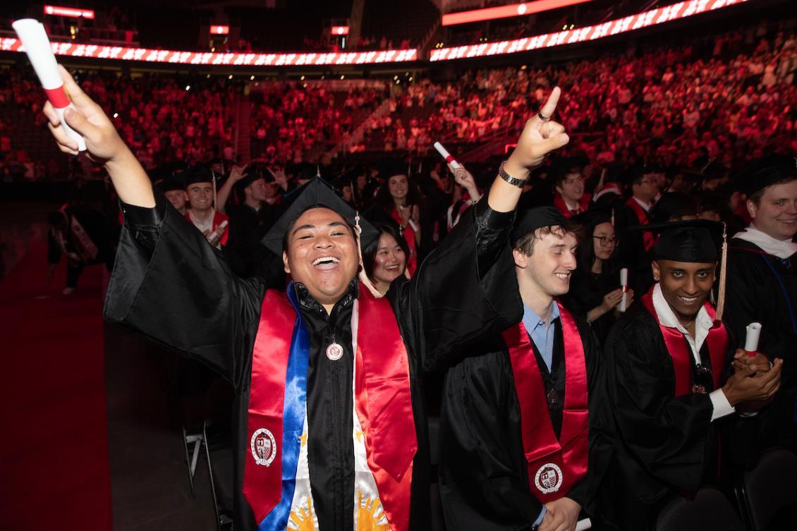 A student celebrating with raised peace signs