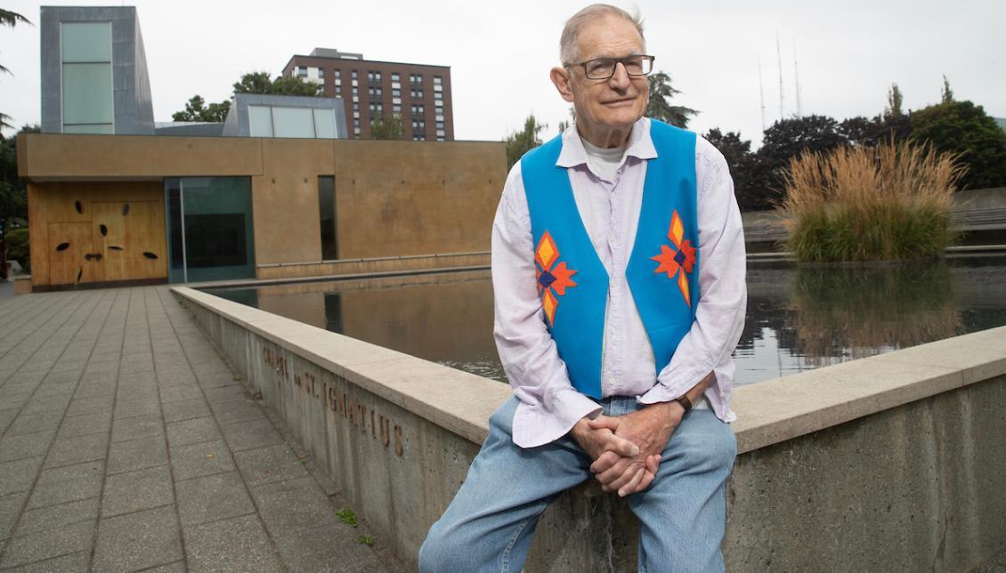 Father Twohy sitting near reflection pool at Chapel of St. Ignatius.