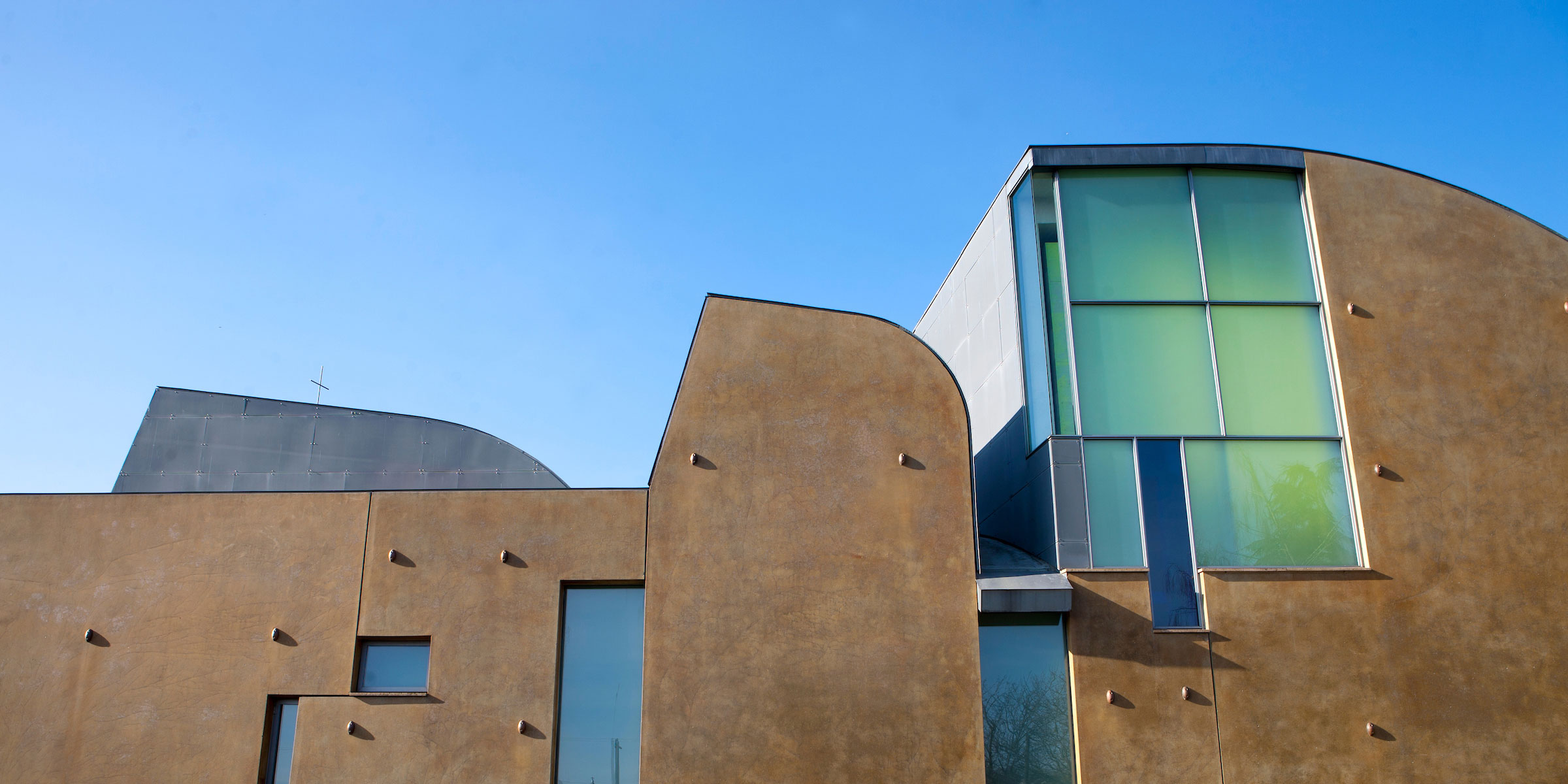 west exterior of St. Ignatius chapel features  a Roman ocher paint finish and modern stained glass windows