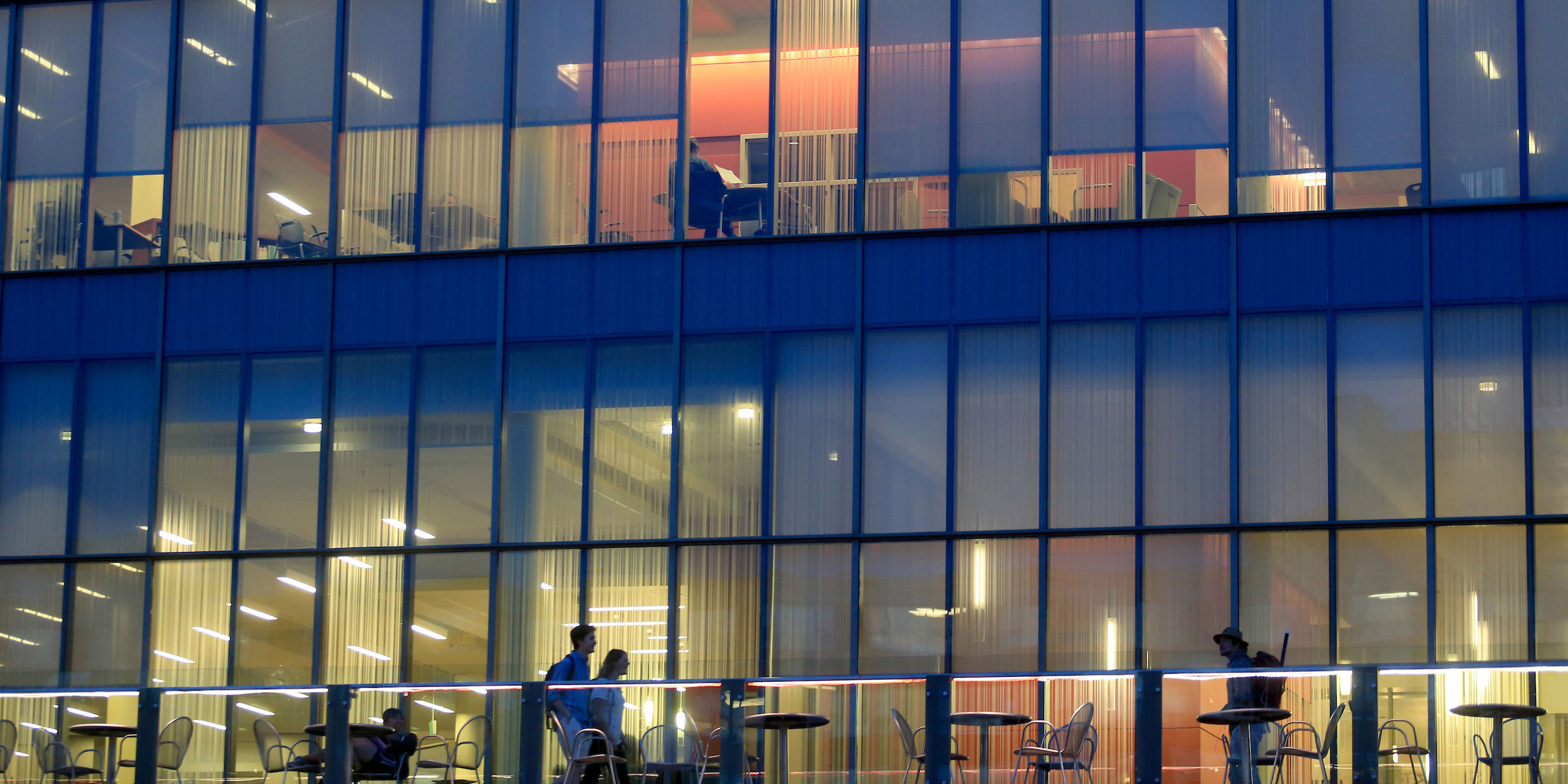 students stroll on the upper deck of Lemieux Library at dusk