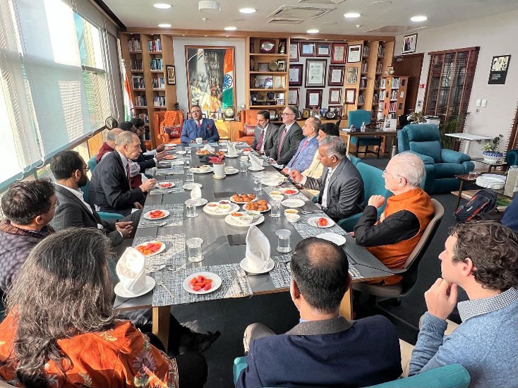 a group of people gathered at a long banquet table listening to a speaker