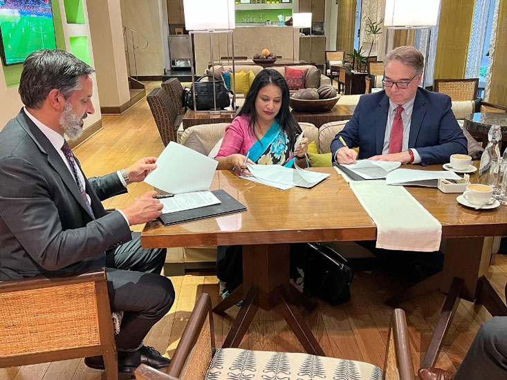 Eduardo Peñalver, Sital Kalantry and others signing papers at a desk