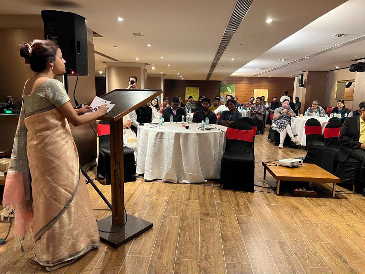 a speaker stands at a podium in front of people sitting at round tables