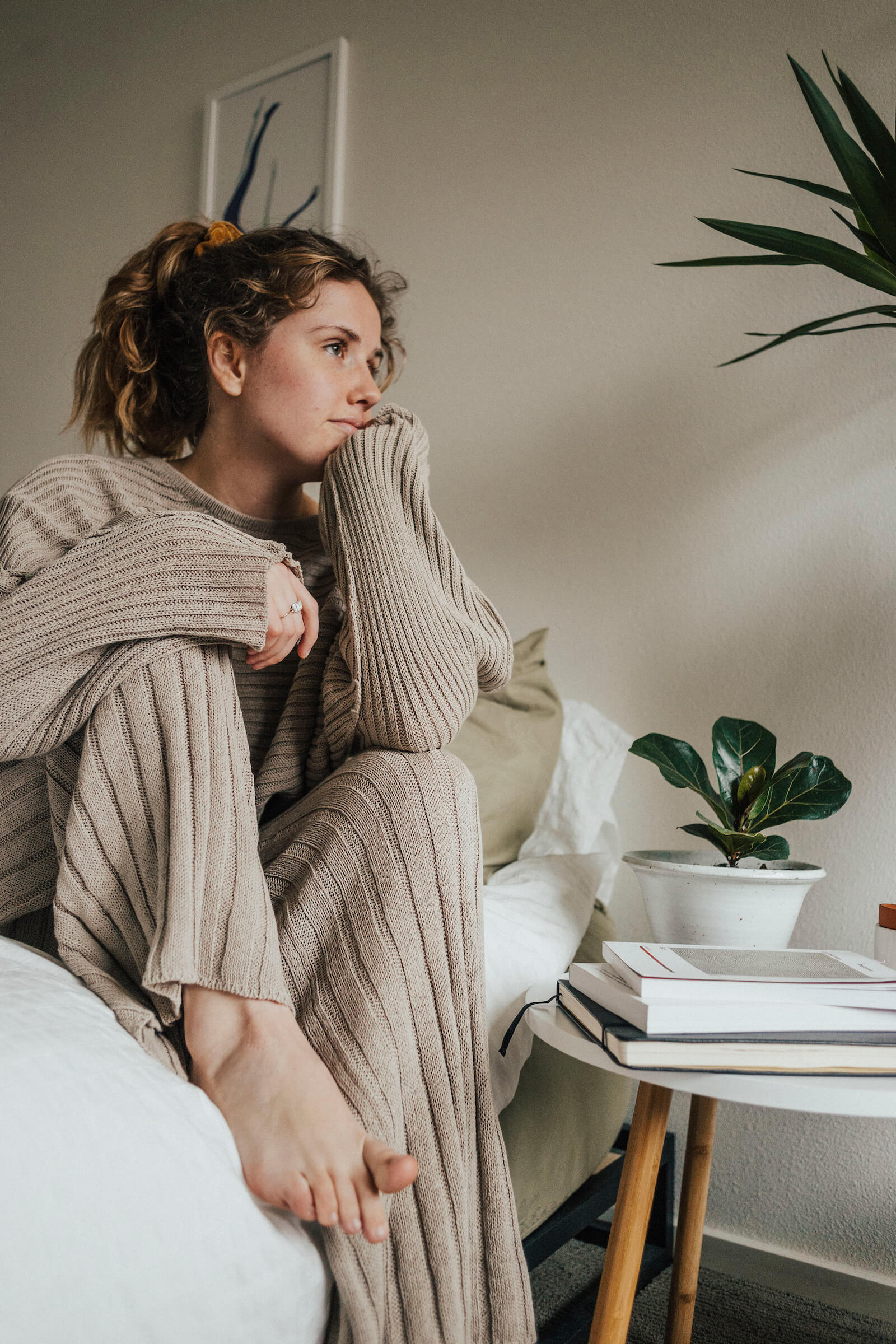 Hallie sits on her bed wrapped in a big comfy sweater