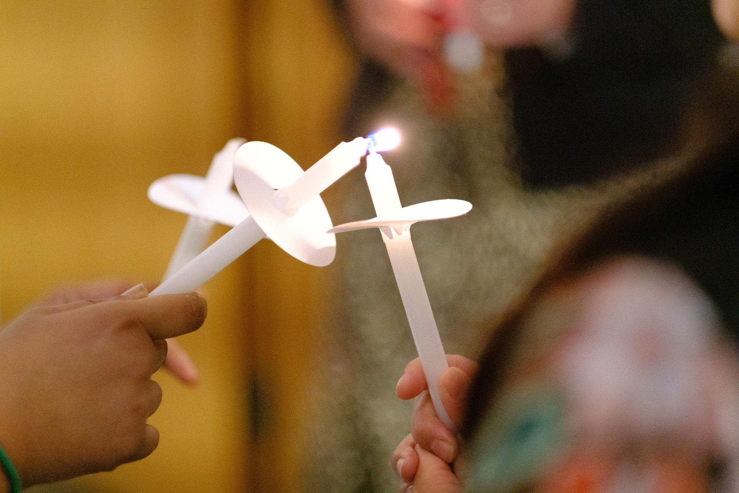 an Advent Mass attendee tips their candle to another's