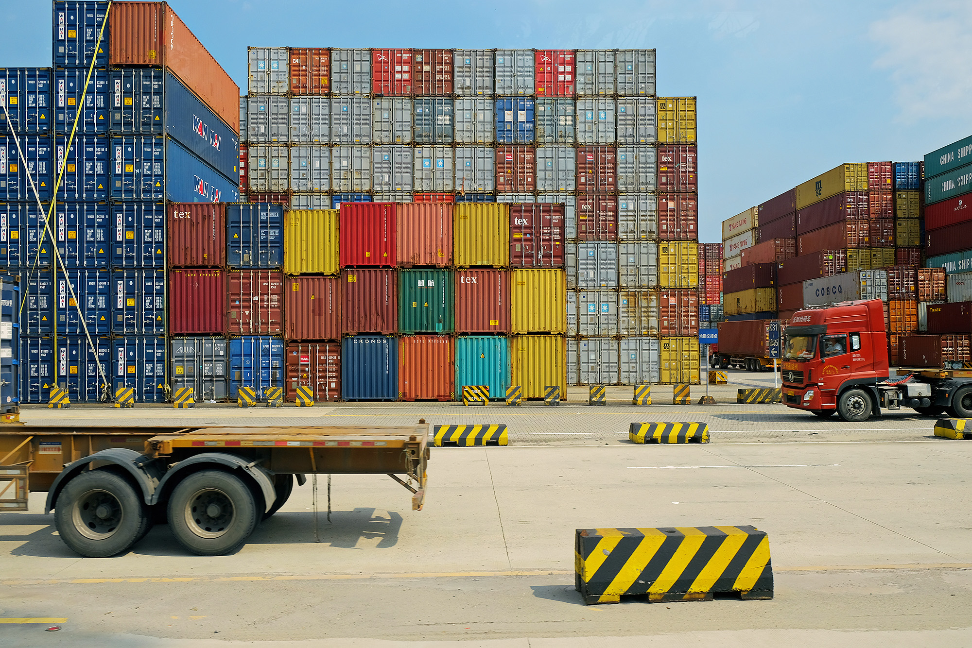 trucks and stacks of colorful shipping containers at a shipyard in China