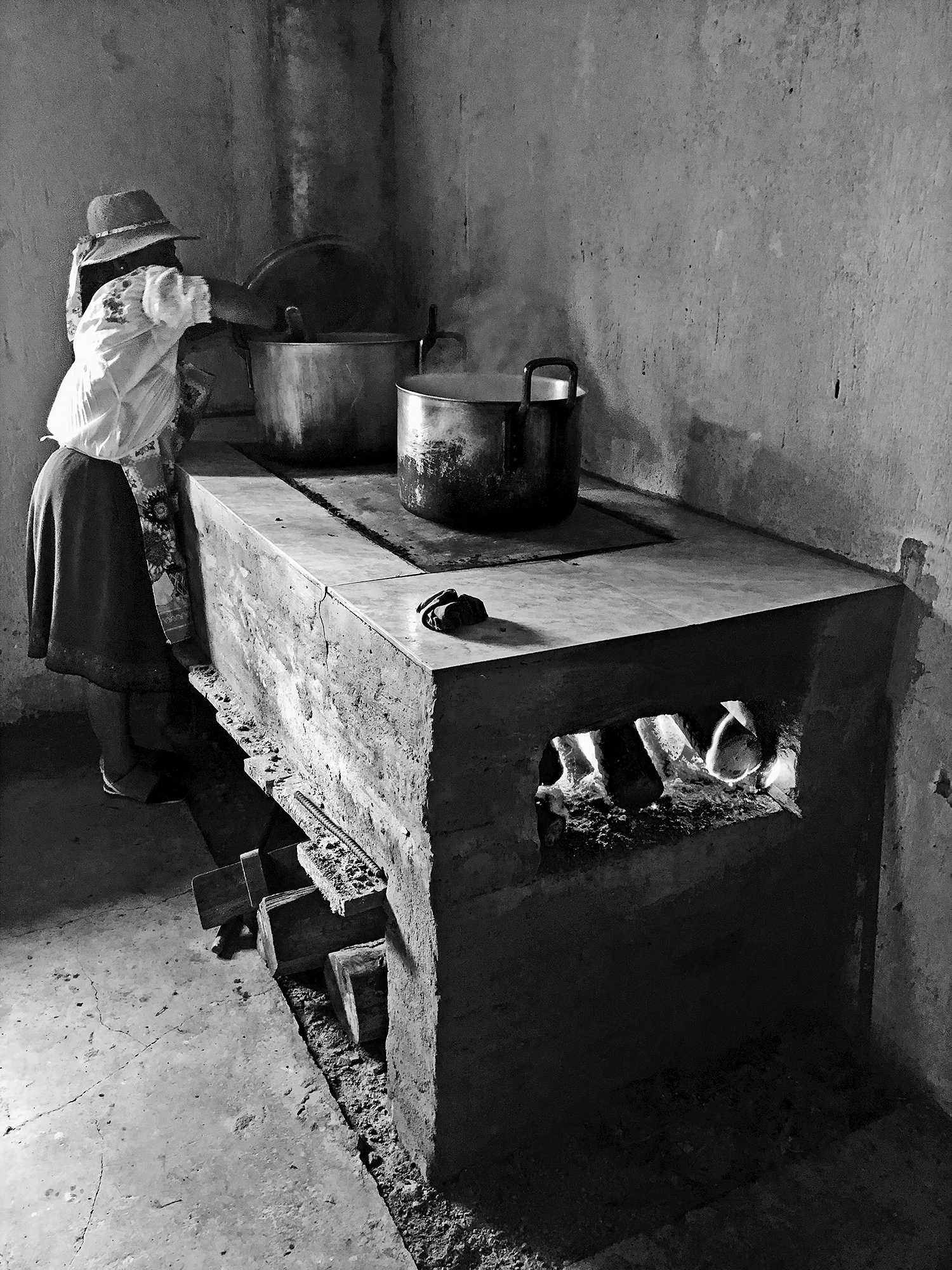  a woman wearing a ribboned straw hat and apron stirs a large stock pot