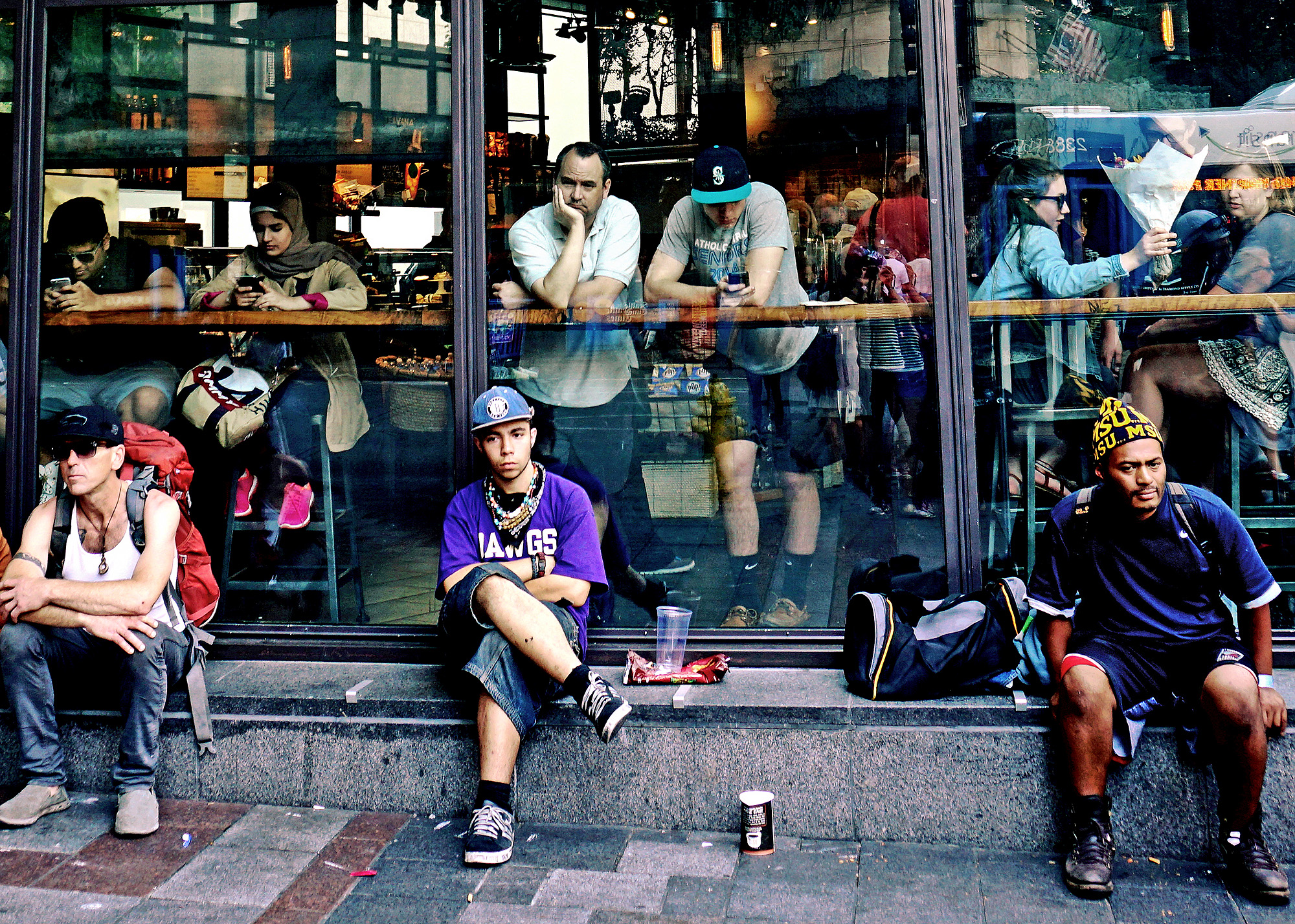 3 men sit alone on the steps outside the Starbucks window of Westlake Square