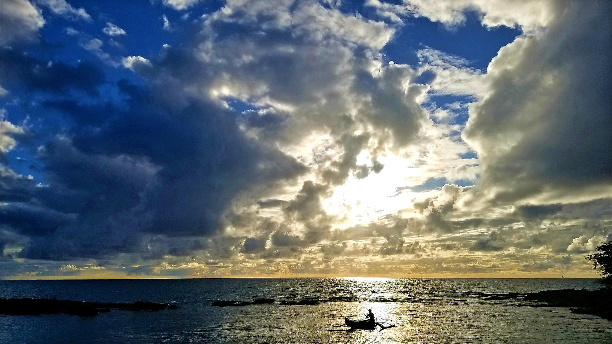 silhouetted sailor on a boat in the Hawaiian sea at sunset