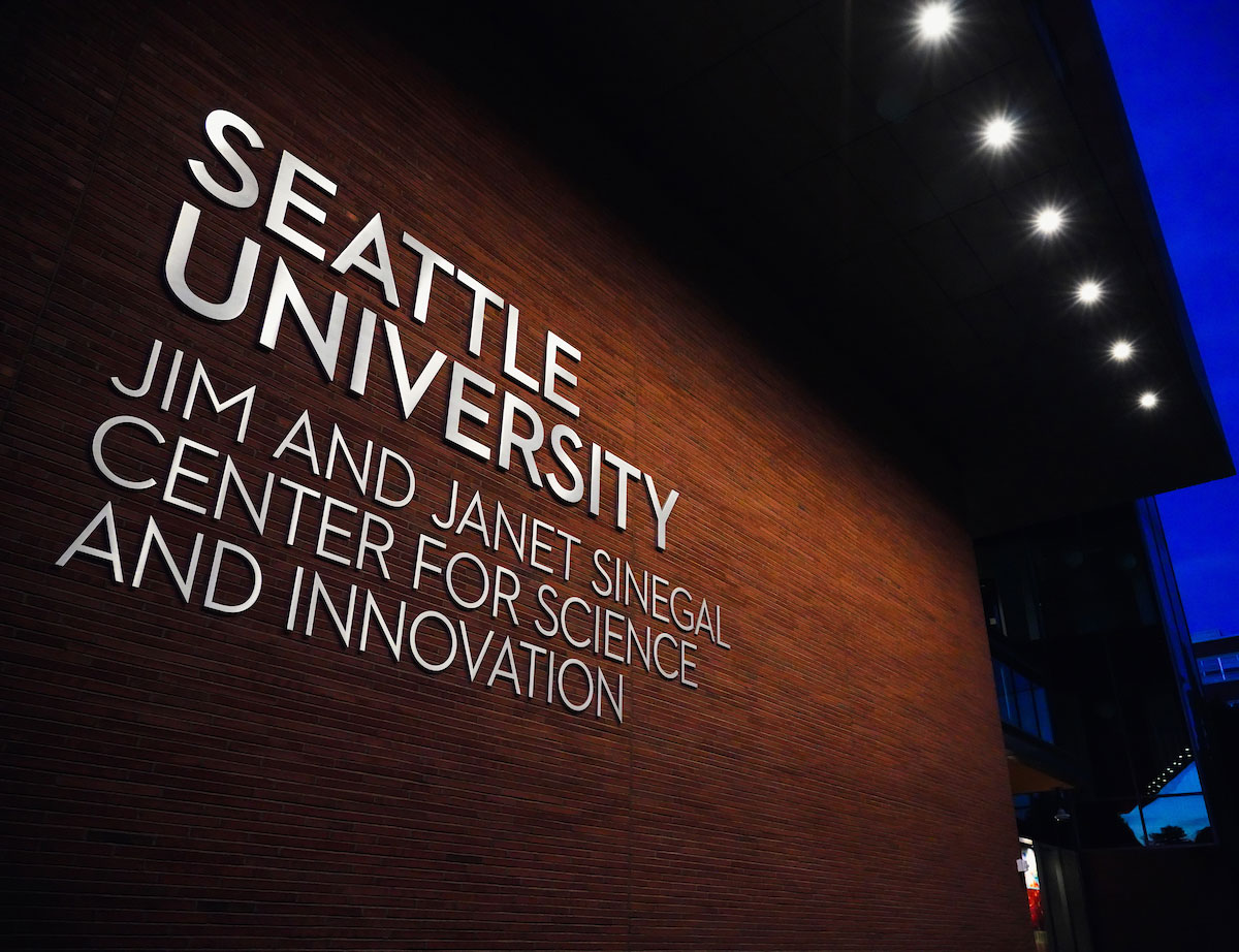 A closeup of the exterior signage of the building with lights overhead.