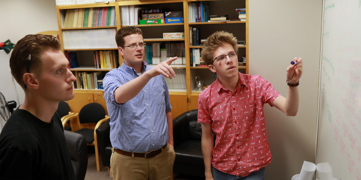 a math professor and two students working on a research project