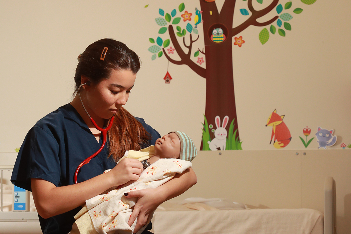 CPL lab technician checks the vitals of one of the baby simulators.